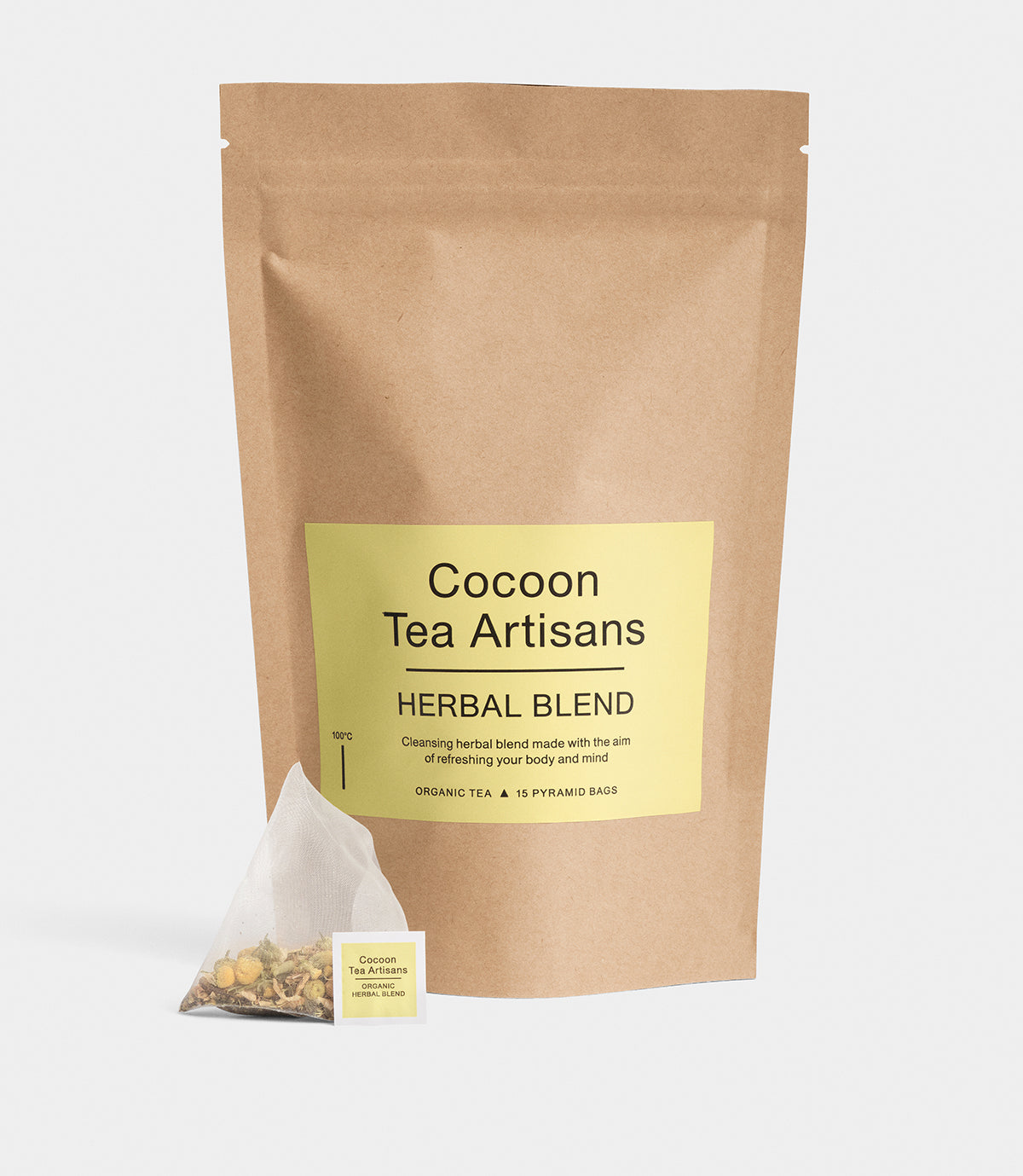 En brun papirspose med teksten "Cocoon Tea Artisans HERBAL BLEND" står. En tepose ligger foran posen, med tekst på etiketten: "Cocoon Tea Artisans ORGANIC HERBAL BLEND."
