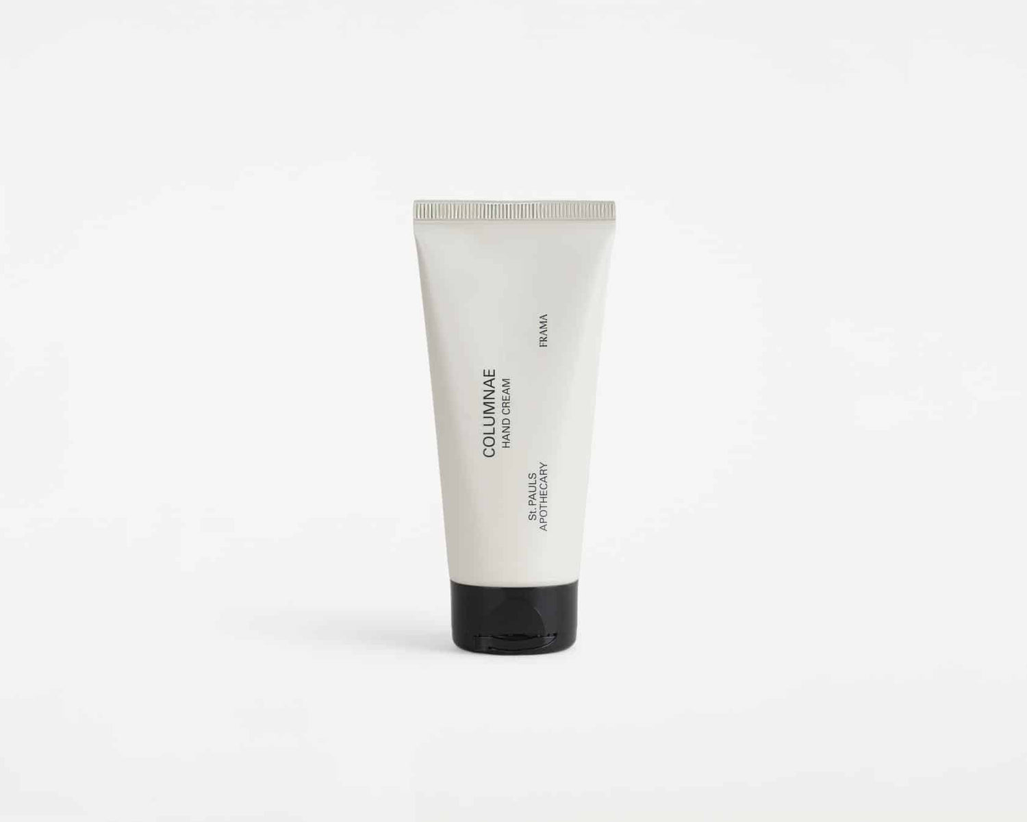 En tube håndcreme står oprejst på en hvid overflade. Tuben er hvid med sort låg, og teksten "COLUMNNAE HAND CREAM," "FRAMA," og "St. PAUL'S APOTHECARY" står på den.