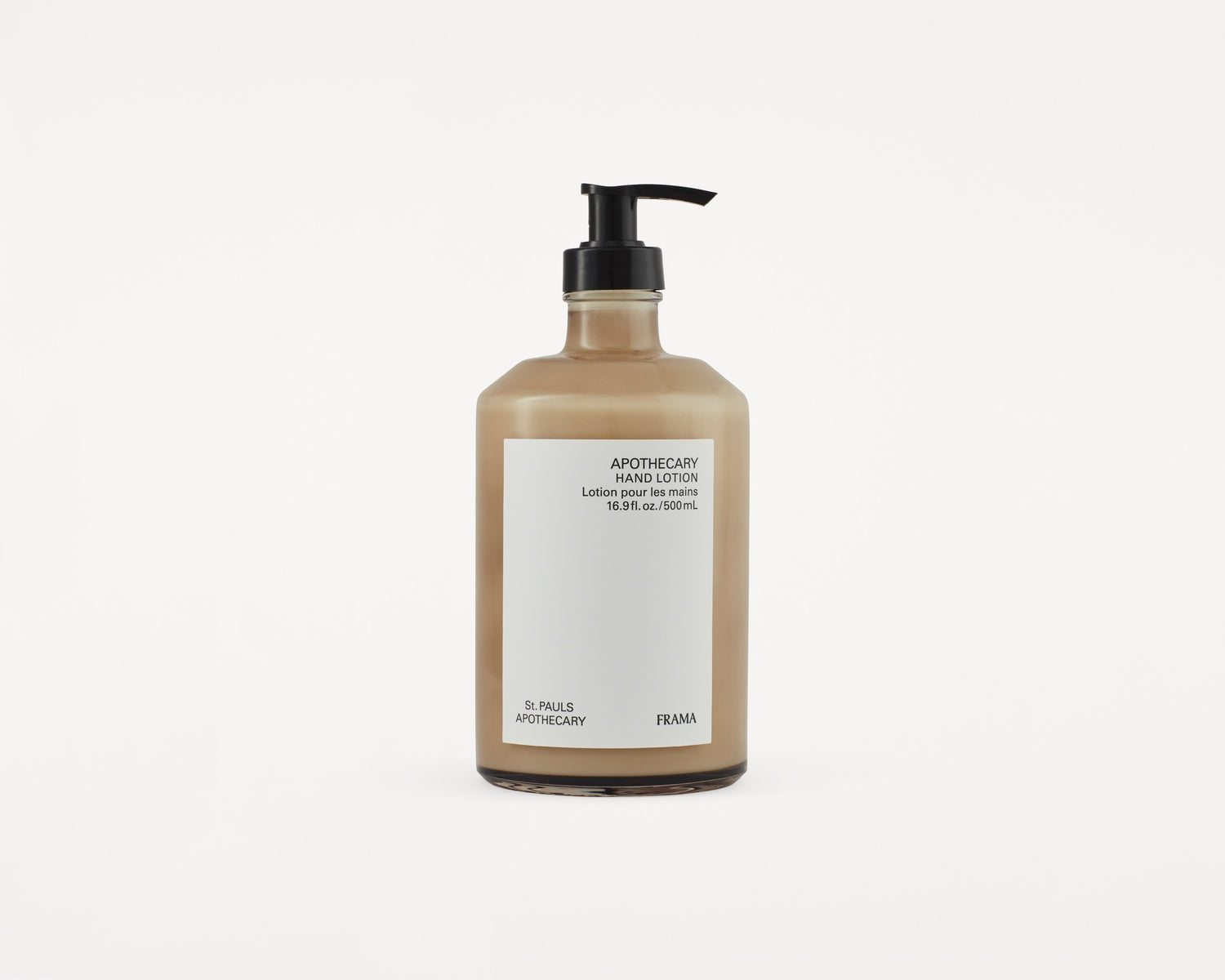 En brun flaske med sort pumpe indeholder lotion og står på en hvid baggrund. Etiket på flasken med teksten: "APOTHECARY HAND LOTION Lotion pour les mains 16.9 fl. oz./500mL St. PAULS APOTHECARY FRAMA".