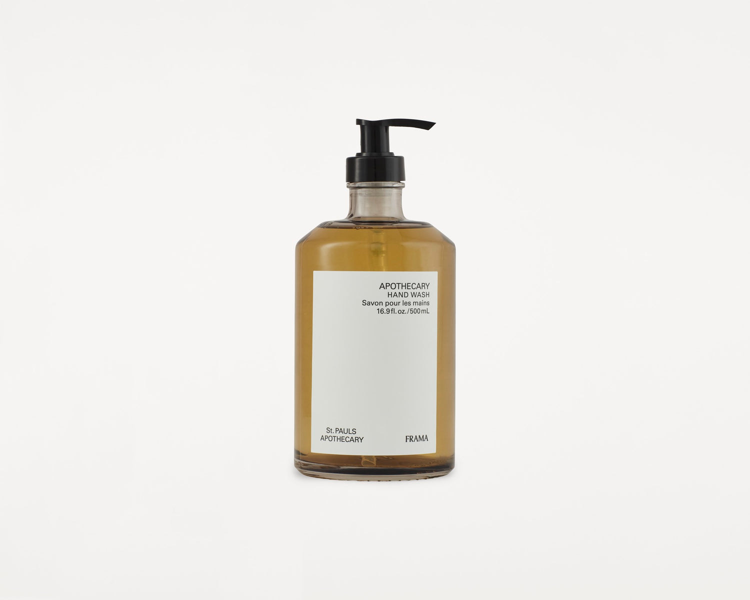 En flaske med håndvask står på en hvid baggrund. Den har en sort pumpe og etiket med teksten "APOTHECARY HAND WASH Savon pour les mains 16.9 fl. oz./500mL, St. PAULS APOTHECARY, FRAMA".