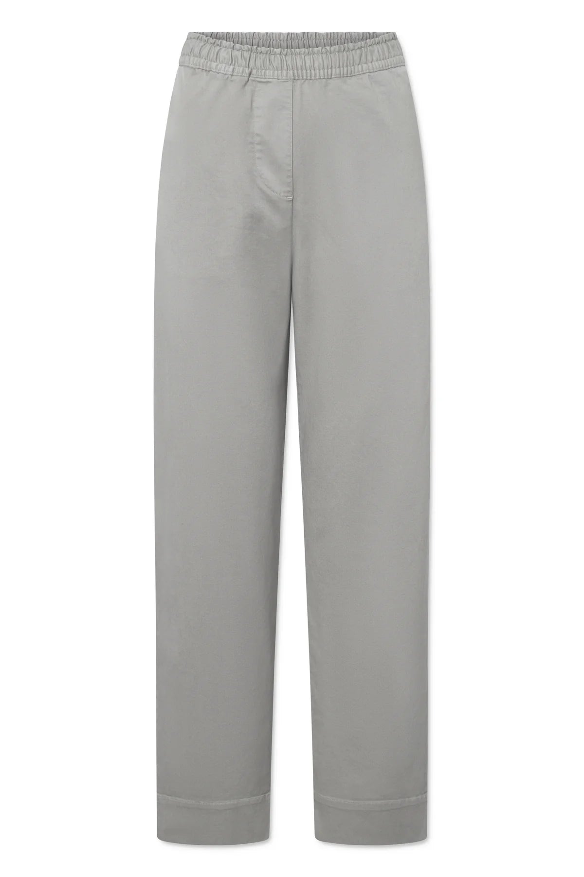 Grå, afslappede bukser med elastik i taljen ligger på et hvidt underlag.