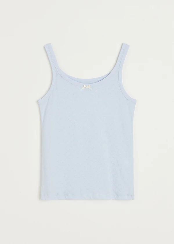 En lyseblå tanktop ligger fladt mod en hvid baggrund. Toppen har tynde stropper og en lille, hvid sløjfe midt på brystet.