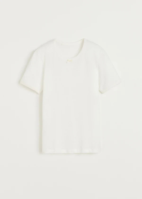 En hvid T-shirt ligger fladt på en ren, hvid baggrund. T-shirten har korte ærmer og en lille detalje ved halsen.