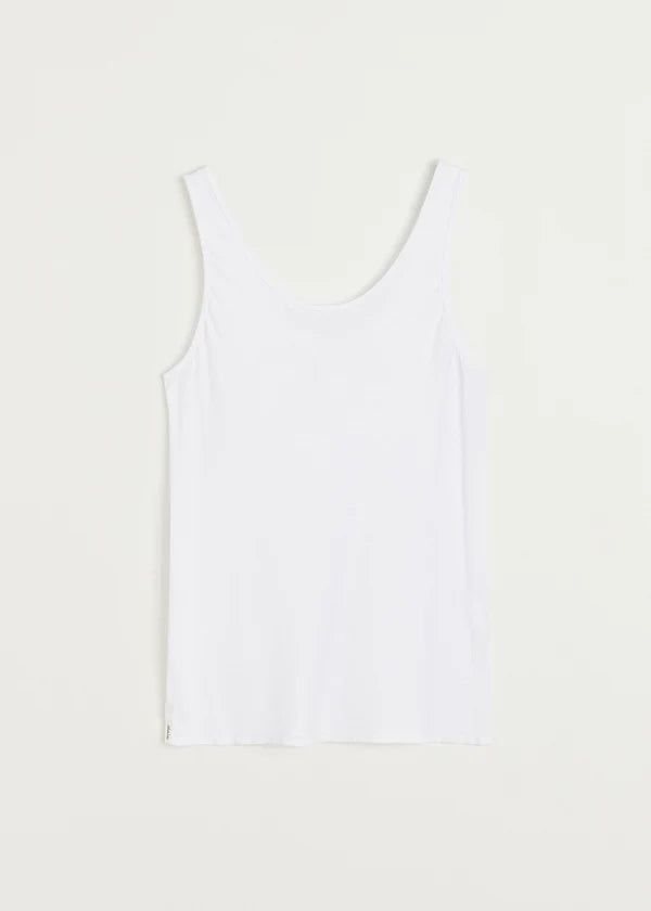 En hvid tanktop hænger ned mod os mod en ren, hvid baggrund. Materialet ser ud til at være ribbede.