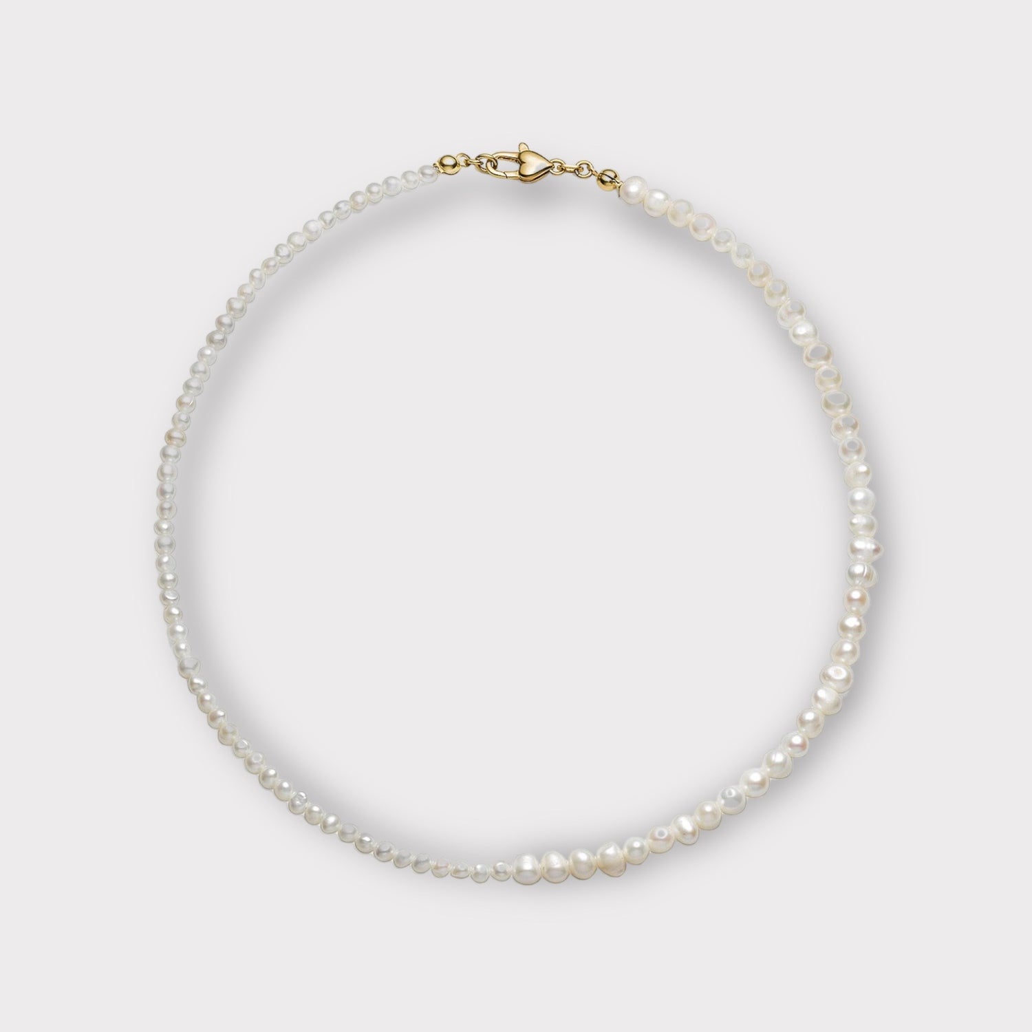 En halskæde af hvide perler ligger i en cirkel på en ensfarvet lys baggrund. Halskæden er lukket med en gylden lås.