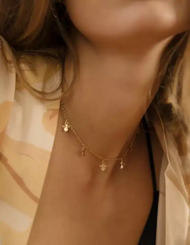 En kvindes hals bærer en guldkæde med vedhæng, der hænger ned. Kæden sidder tæt om hendes hals i en afslappet kontekst.