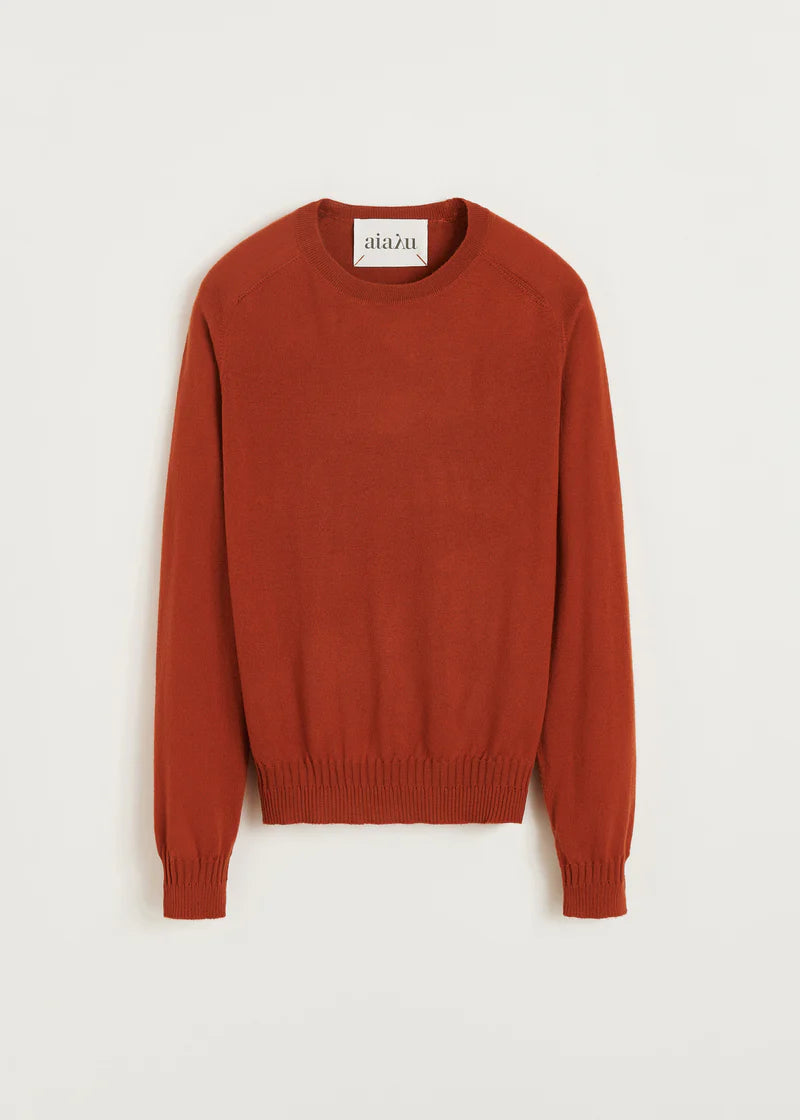 En brun sweater med etiketten "aiazu" i nakken ligger foldet ned mod en hvid baggrund.