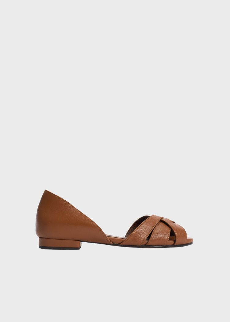 En brun lædersandal med åben tå vises mod en ensfarvet, lys baggrund. Sandalen har krydsende remme over forfoden og en lav hæl.