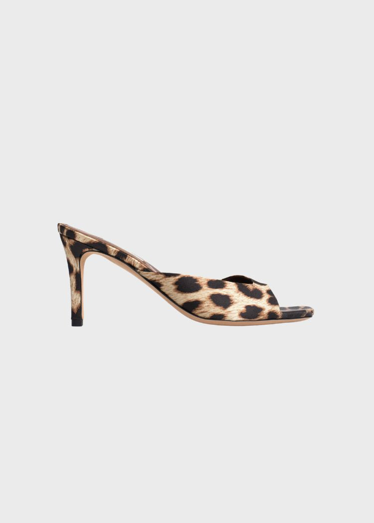 En leopardmønstret sandal med hæl ses i profil. Sandalen er centreret mod en neutral, lysegrå baggrund.