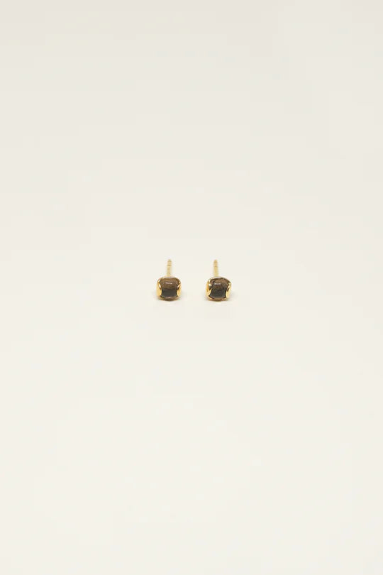 To små guldøreringe med mørke, firkantede sten sidder på en ren, hvid baggrund.