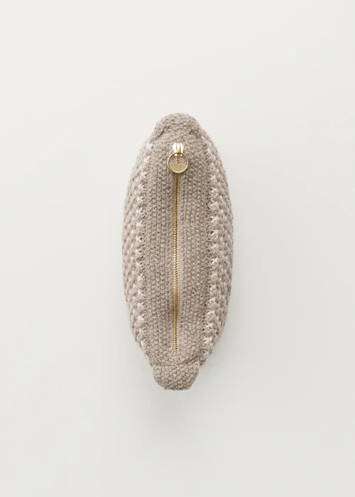 En beige, oval strikket taske ligger fladt på en hvid overflade. En gylden lynlås løber ned ad midten af tasken.