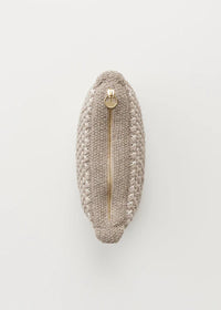 En beige, oval strikket taske ligger fladt på en hvid overflade. En gylden lynlås løber ned ad midten af tasken.