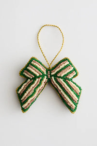 En perlebesat sløjfe ornament, med grønne, beige og hvide striber, hænger fra en guld tråd løkke på en hvid baggrund.